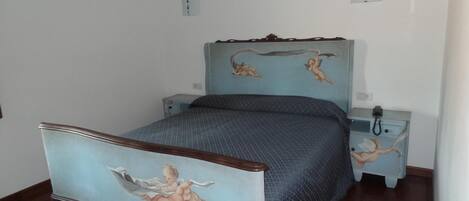 A bedroom with a bed, two bedside tables, and a wall with a mural.