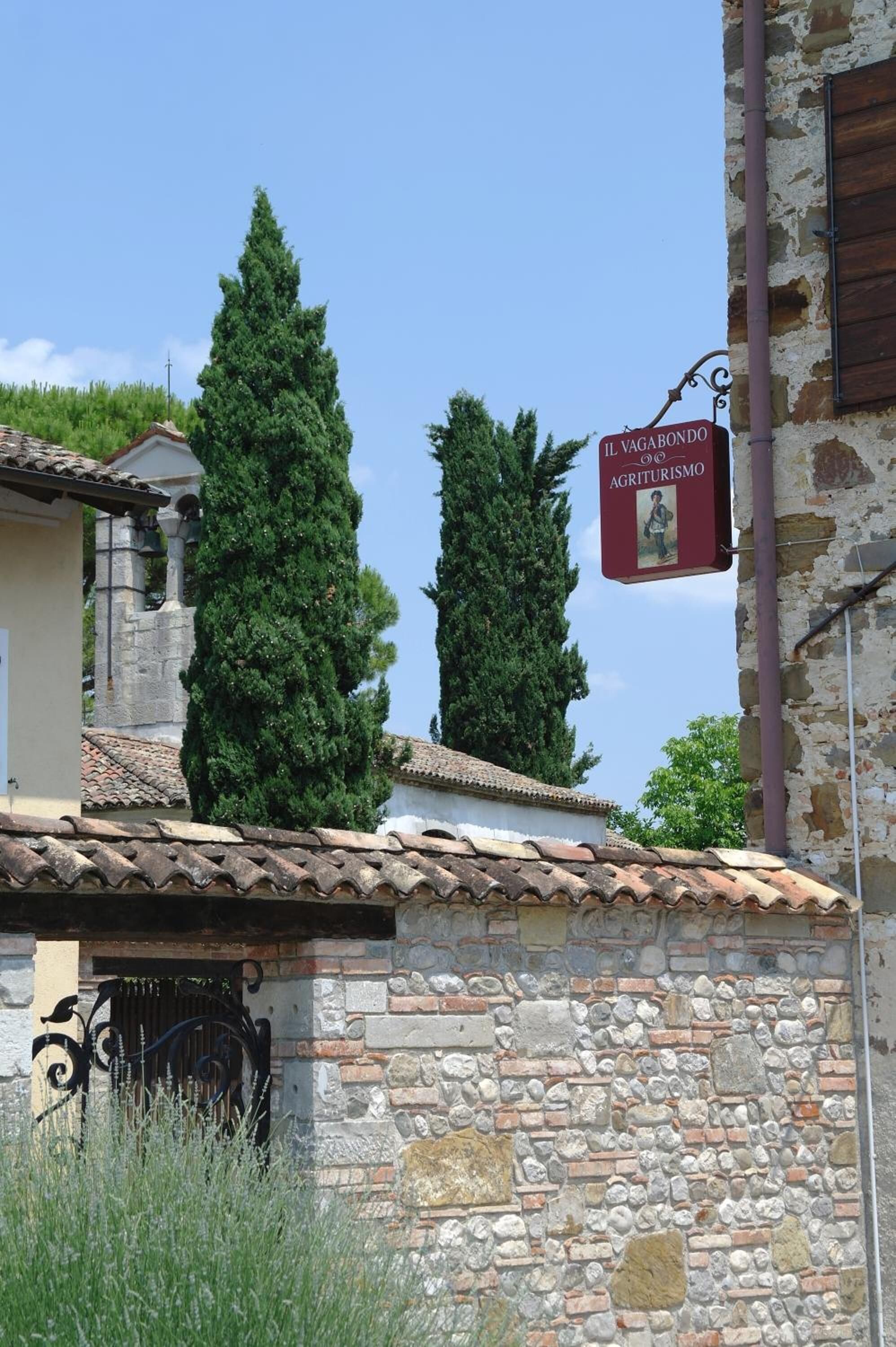 A stone building with a tiled roof and a sign indicating 'Il Vagabondo Agriturismo'.