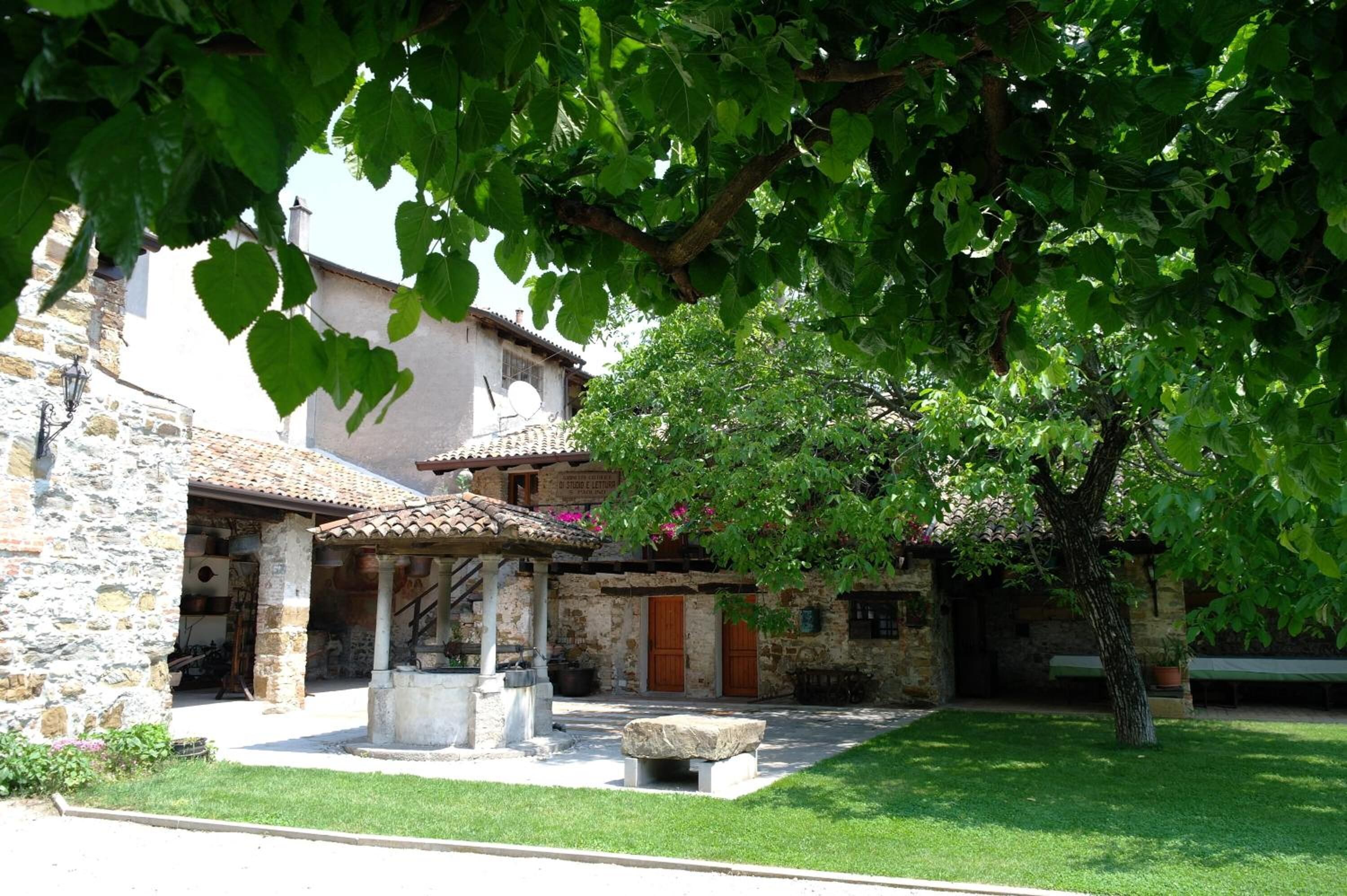 Un edificio de piedra con un patio, una fuente y un árbol que da sombra.