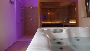 A spa room with a hot tub, a shower area, and wooden beams on the ceiling. - Il Vagabondo (Buttrio)