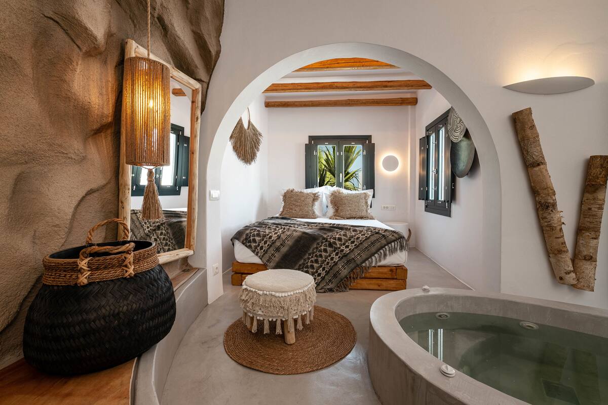 A bedroom with a bed, a large window, a bathtub, and a woven basket.