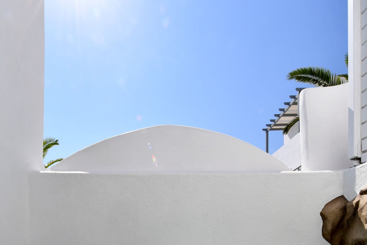 A clear blue sky, a swimming pool, and white walls.