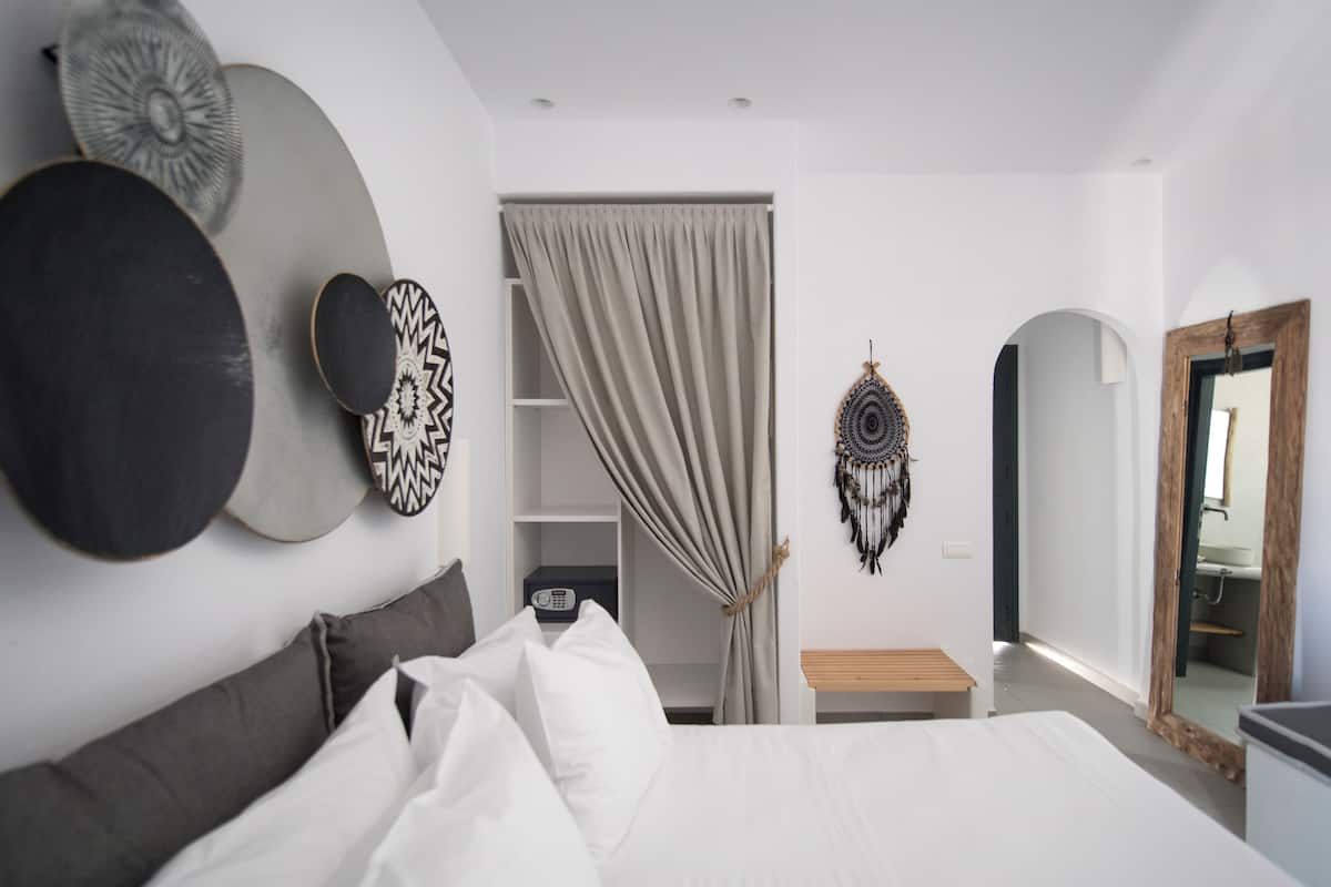 A modern bedroom with a bed, a bedside table, a wardrobe, and a mirror.