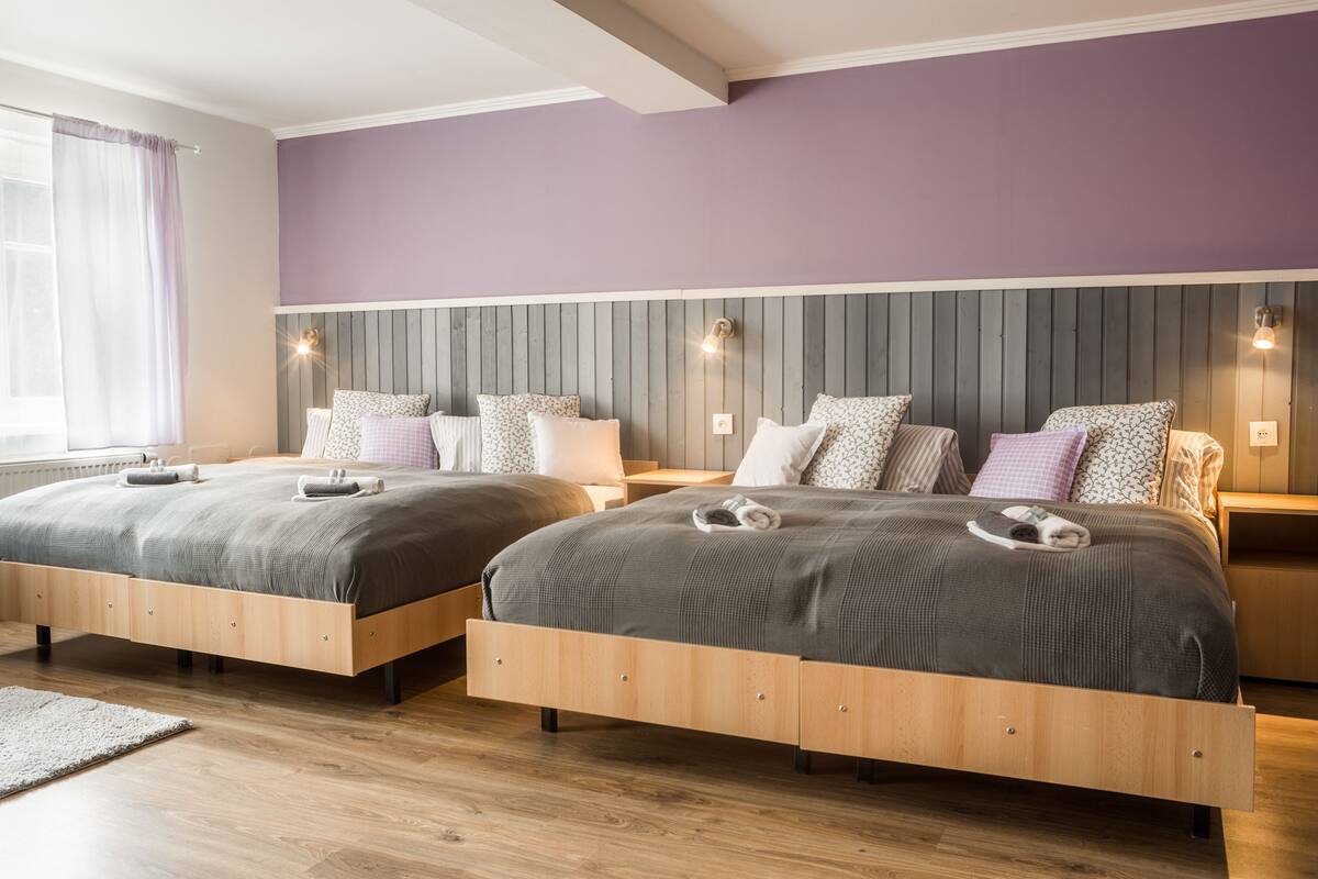 A double room with two beds, each with a headboard, bedside tables, and lamps.