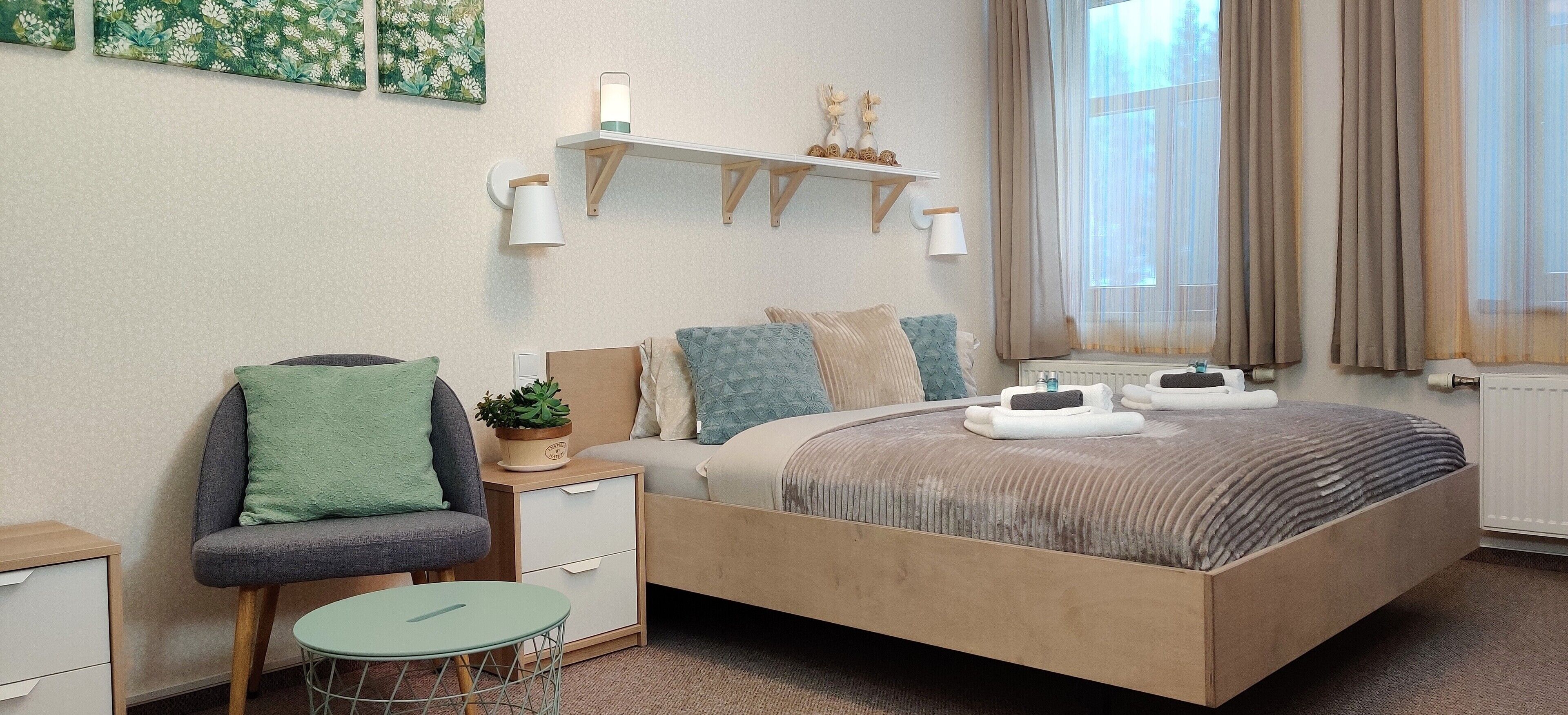 Une chambre moderne avec un grand lit, des tables de chevet, une petite table ronde et une plante en pot.