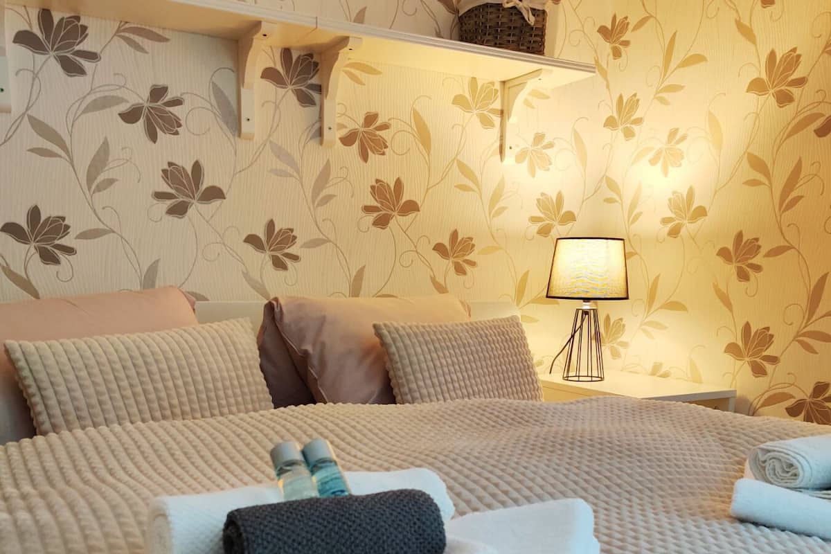 A neatly made bed with pillows, a folded towel, and a bottle of water on the bed.