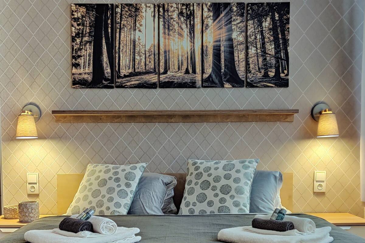 A neatly made bed with two pillows, a headboard, and two bedside lamps.