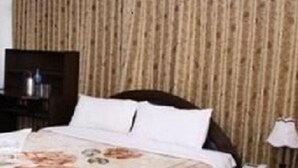 A hotel room with a large bed, a wooden headboard, and a curtain covering the window. - Hotel Aradhya Palace (Kathmandu)
