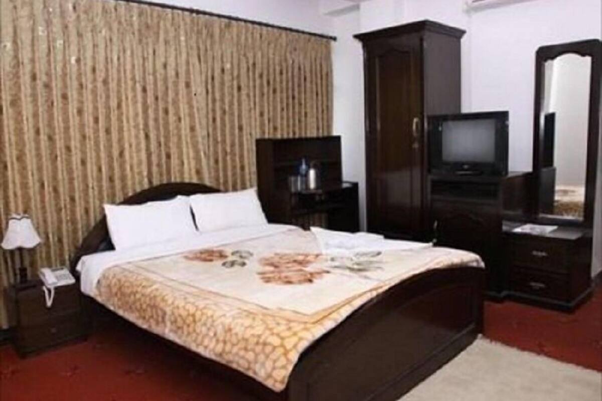A hotel room with a bed, a television, a wardrobe, and a mirror.