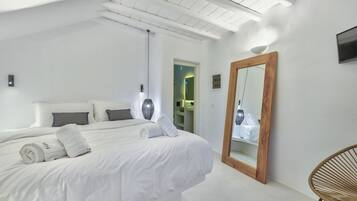 Un dormitorio moderno con una cama grande, un espejo con marco de madera y una silla de mimbre.
