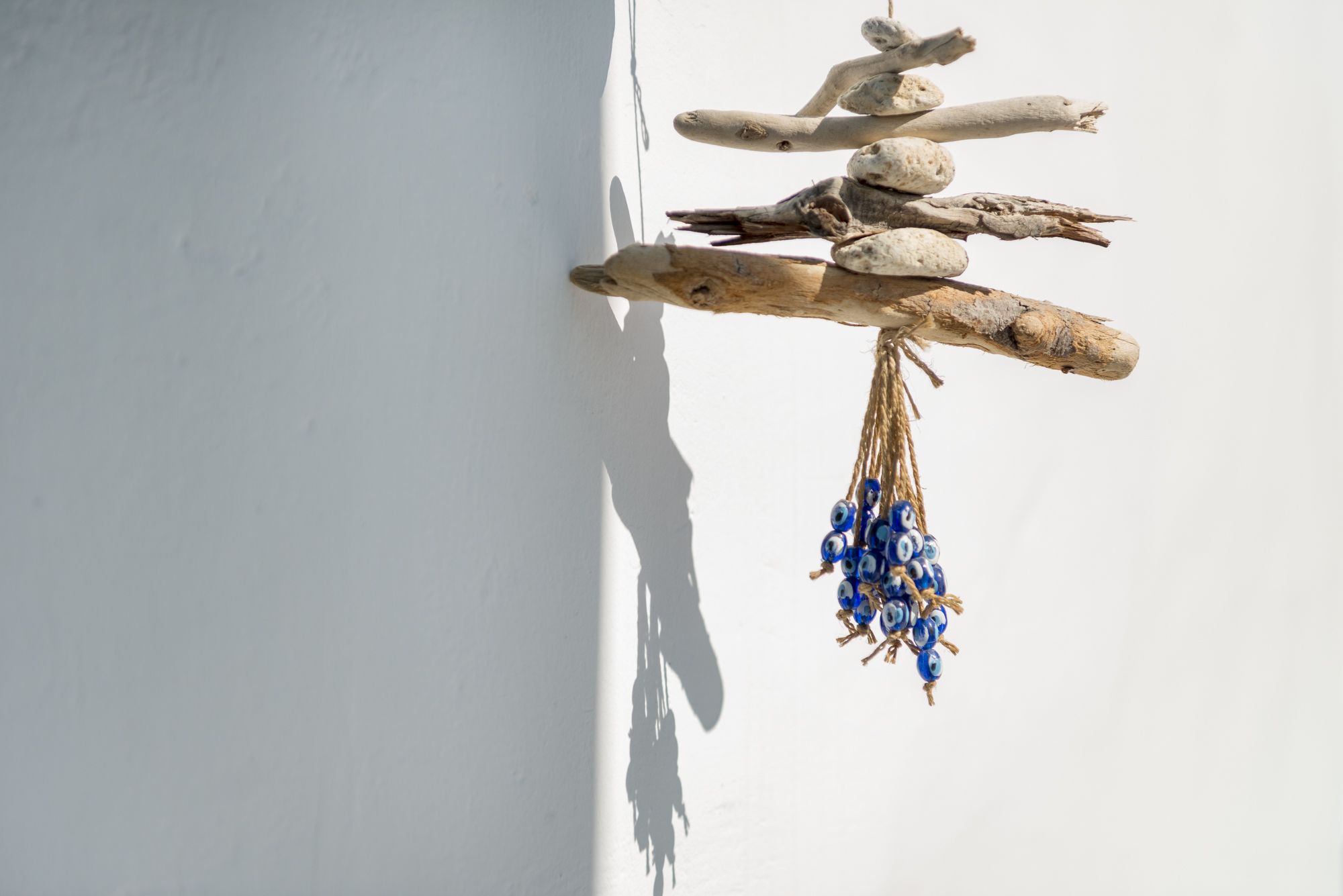 Een wanddecoratie met takken en blauwe kralen.