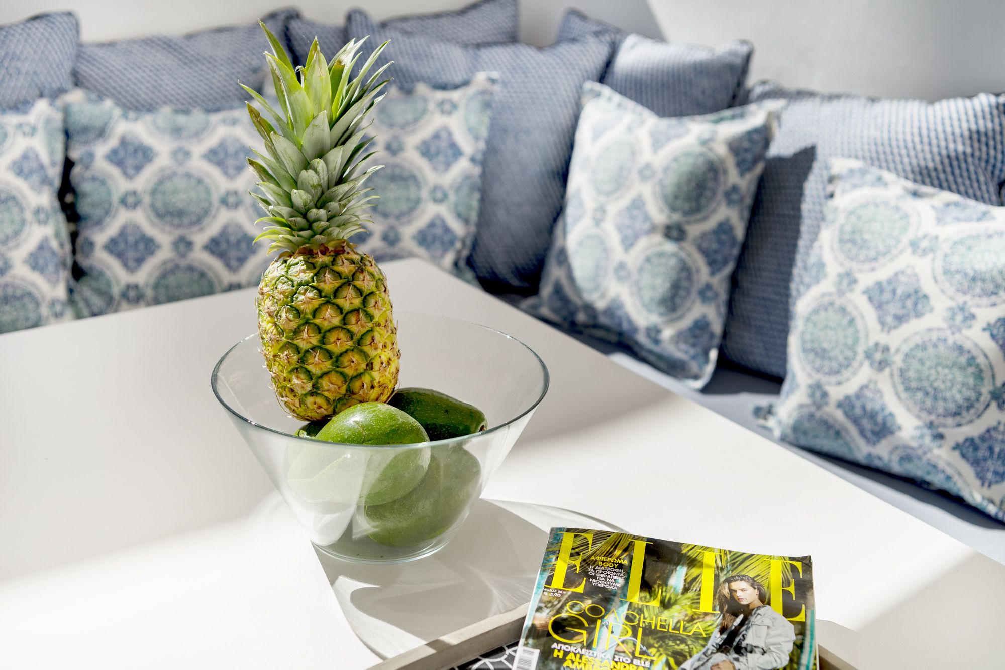 Una piña en un bol de cristal sobre una mesa blanca con una revista.