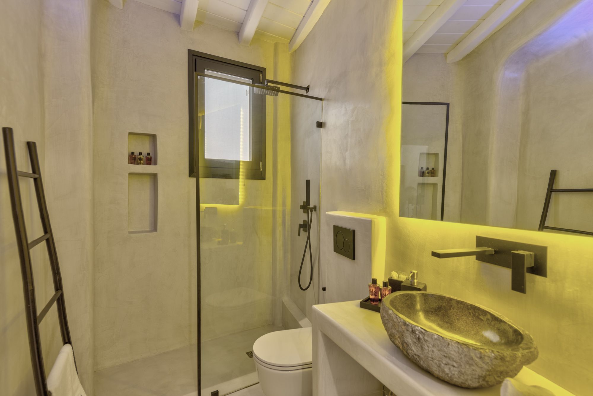 A modern bathroom with a glass-enclosed shower, a white toilet, and a large stone sink.