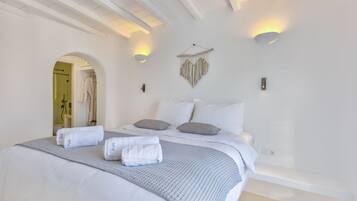 Ein Schlafzimmer mit einem großen Bett, zwei Wandleuchten, einem Wandbild und einer sichtbaren Badezimmertür.