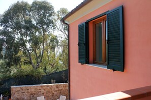 Un edificio con un muro in pietra e una finestra con persiane verdi.