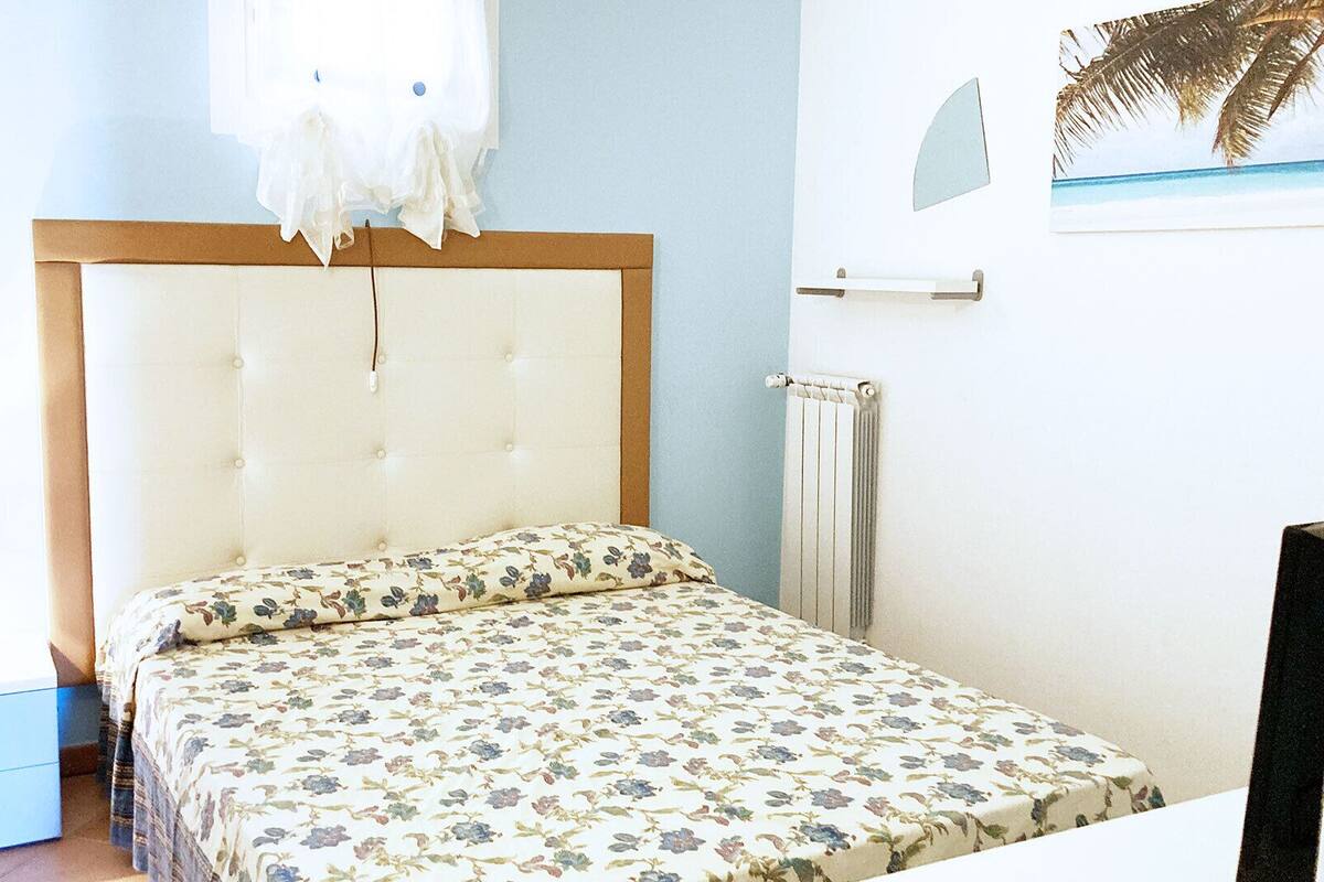 A bedroom with a bed, a nightstand, a dresser, and a radiator.
