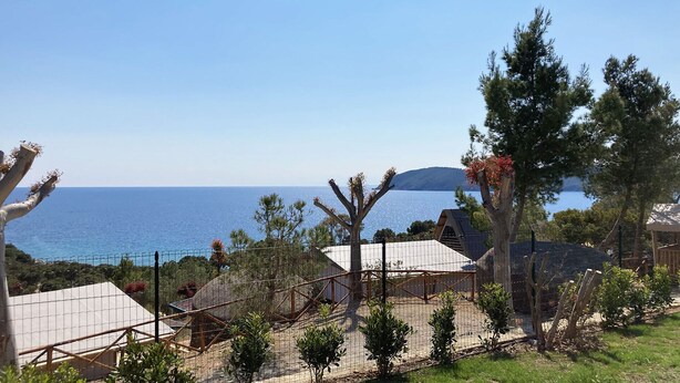 A coastal property with a fenced garden, a white tent-like structure, and a view of the sea. - Appartamenti La Risacca (Capoliveri)