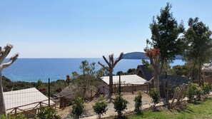 Una propiedad costera con jardín cercado, una estructura blanca similar a una carpa y vista al mar.