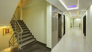 A modern hotel corridor with a staircase, a framed picture on the wall, and a clean, tiled floor. - Windsor Castle Inn (Bengaluru)