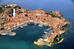 An aerial view of a coastal town with a marina, historic buildings, and a prominent fortification. - Appartamento Cosmopoli (Portoferraio)