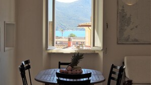 A dining area with a table and chairs, a window with a view of a mountain and sea, and a framed map on the wall.
