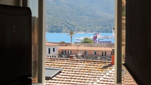 A view from a window overlooking a coastal area with a ship named "Toremar" docked at a port.