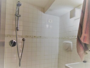 A bathroom with a shower, a toilet, and a towel rack.
