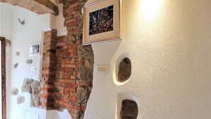 A room with exposed brick walls, a framed picture, and two wall-mounted planters. - Da Gabriella e David (Marciana)