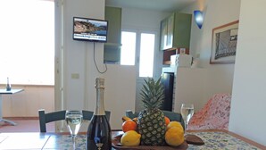 A dining table with a bottle of wine, a pineapple, oranges, and a glass of water. - Residence Le Solane (Campo nell'Elba)