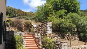 A stone staircase leading up a hill, surrounded by greenery and a stone wall. - Residence Le Solane (Campo nell'Elba)