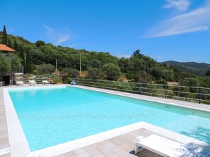 Una piscina al aire libre, sillones reclinables de piscina