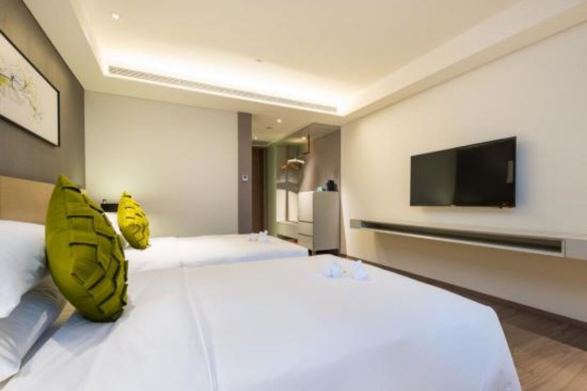 Une chambre d’hôtel avec deux lits, un téléviseur à écran plat fixé au mur et un design moderne.