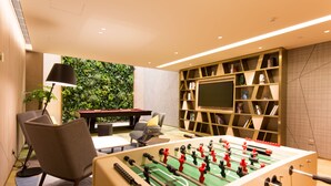 Een moderne kamer met een tafelvoetbaltafel, een televisie en een boekenkast.
