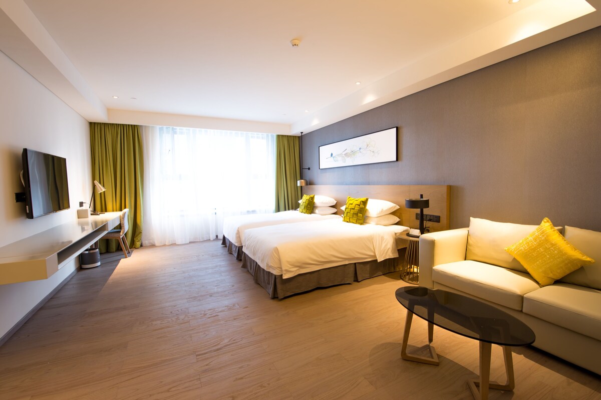 Une chambre d’hôtel moderne équipée d’un lit, d’un canapé, d’une télévision et d’un bureau.