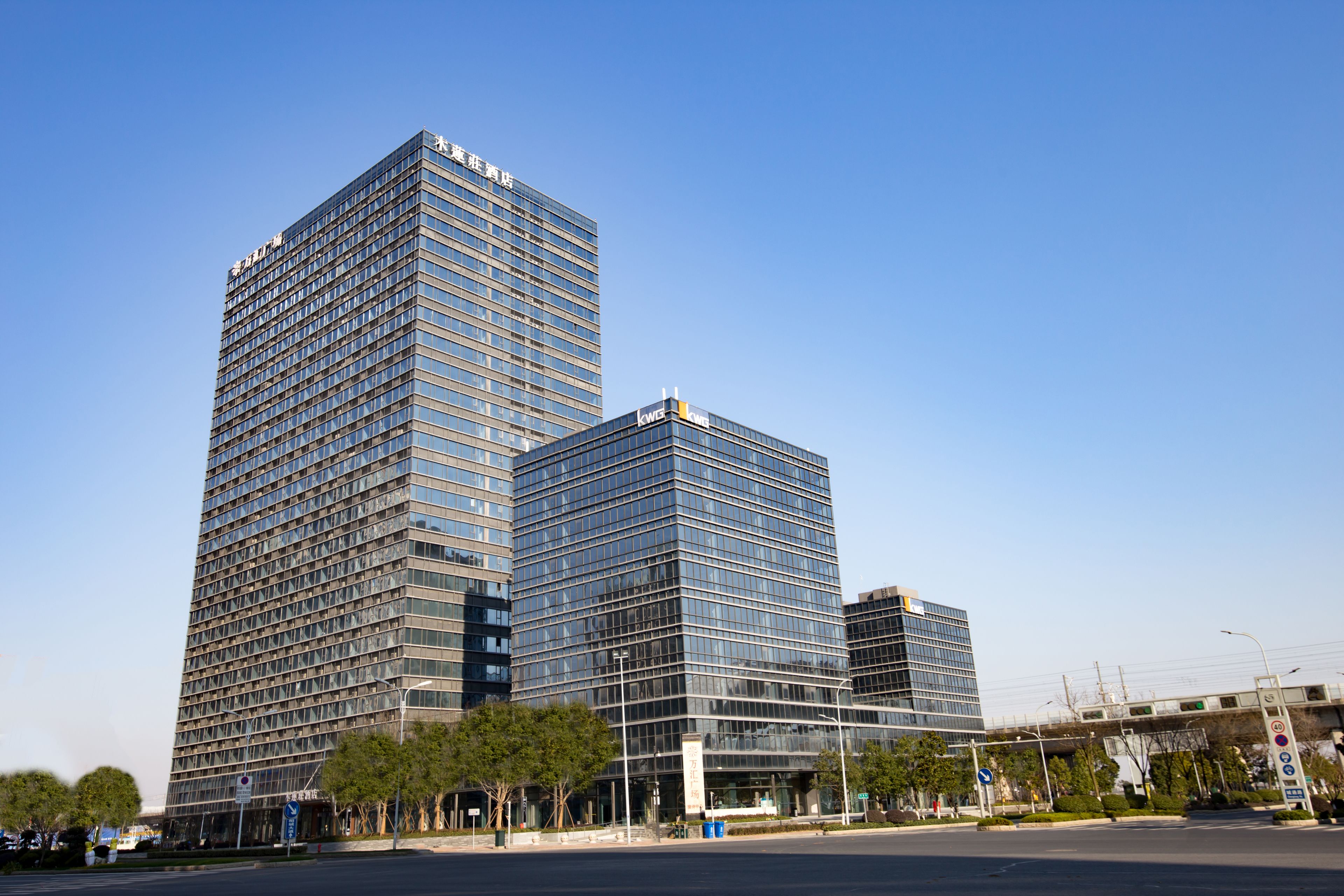 A modern high-rise building with a glass facade, multiple floors, and a prominent sign at the top.
