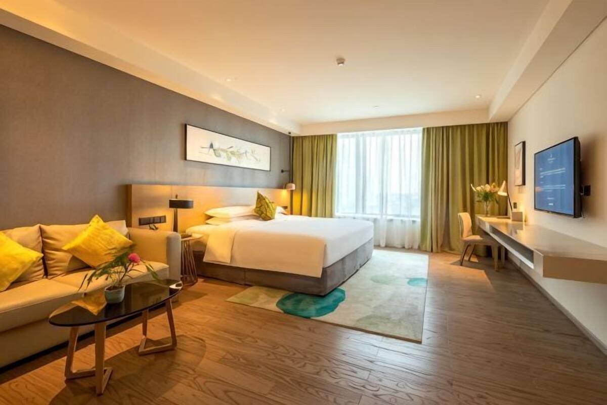Une chambre d’hôtel avec un lit, un canapé, un bureau et une télévision.