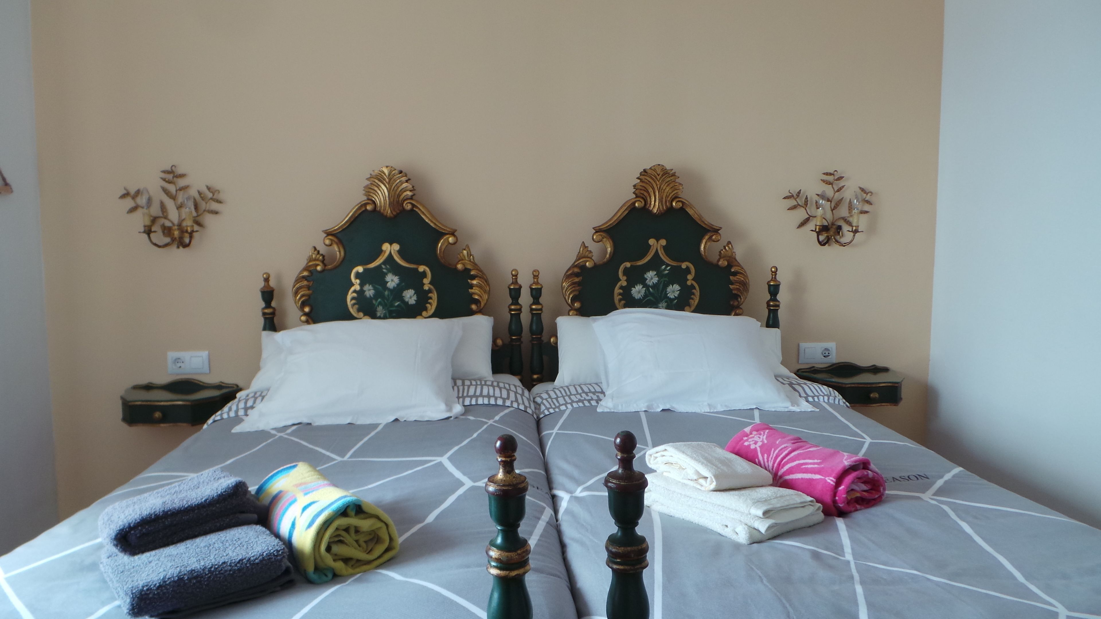A double bed with ornate headboards, two bedside tables, and neatly folded towels.