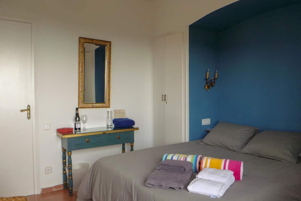 Une chambre à coucher avec un lit, une commode, un miroir et un mur d’accent bleu.