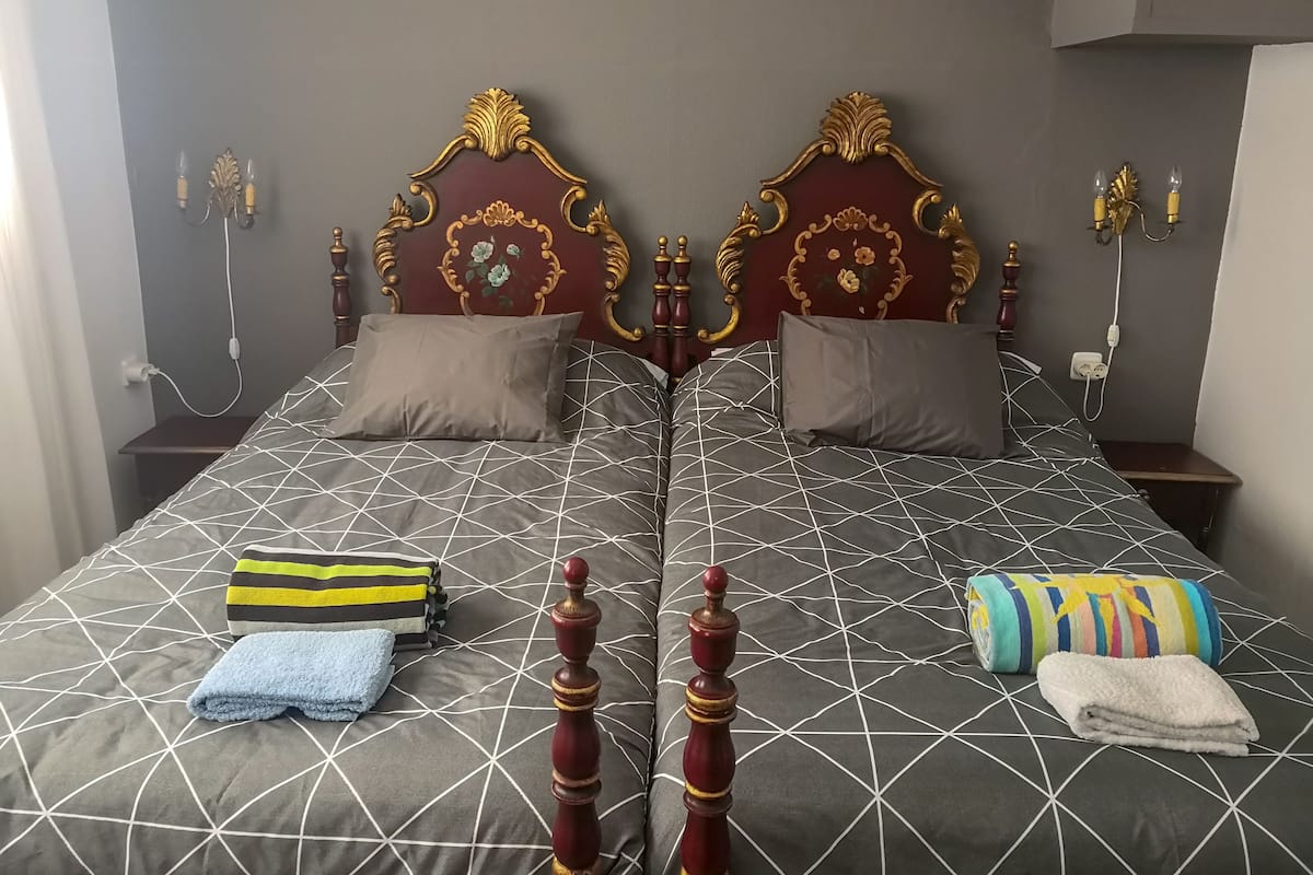 Un lit double avec une couvre-lit à motifs géométriques, deux oreillers et une tête de lit en bois.