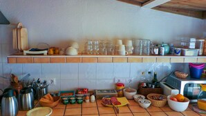 Een keuken met een betegelde spatwand, een magnetron en diverse keukengerei en apparaten.