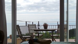 Een balkon met een tafel, stoelen, een fles wijn en een bloempot.