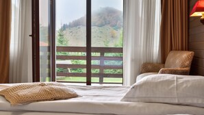 Une chambre avec une grande fenêtre, un lit, une chaise et une lampe.