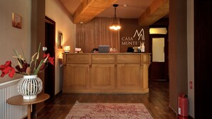 Un espace d’accueil avec un comptoir en bois, un ordinateur portable et une enseigne indiquant « CASA MUNTE ».