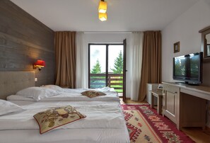 A hotel room with a bed, a desk, a television, and a window with curtains. - Casa Muntelui Fundata (Moieciu de Jos)
