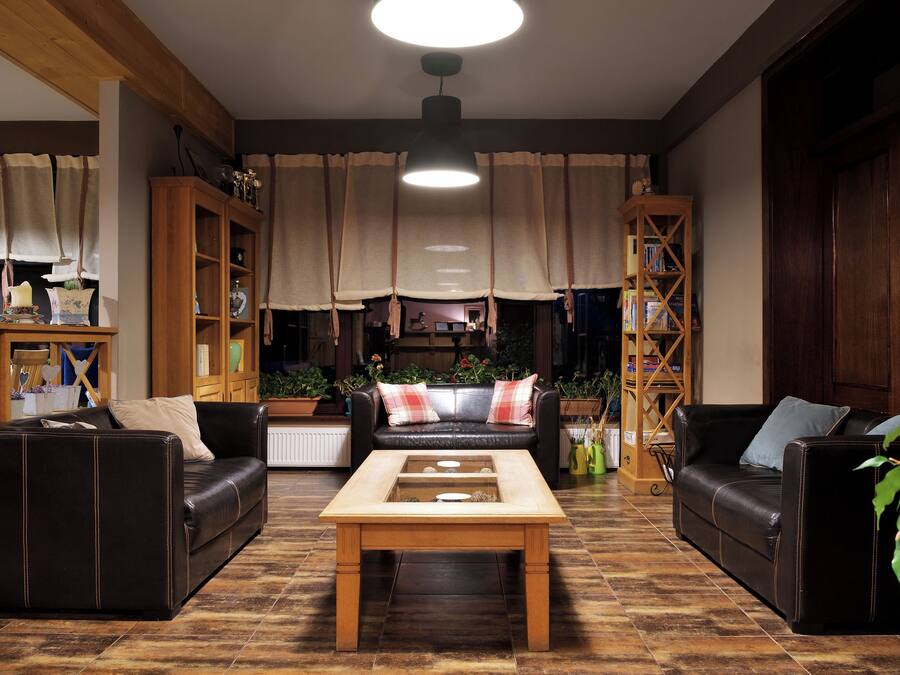 A cozy living room with two leather sofas, a wooden coffee table, and a bookshelf.