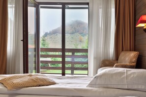 Une chambre avec une grande fenêtre, un lit, une chaise et une lampe.