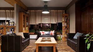Un salon chaleureux avec deux canapés en cuir, une table basse en bois et une grande fenêtre agrémentée de rideaux.