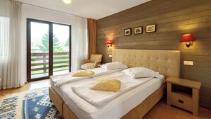 Ein Doppelbett mit Holz Kopfteil, zwei Nachttische und ein großes Fenster mit Vorhängen.