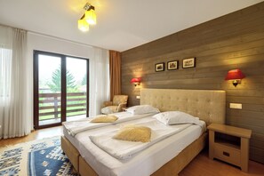 Une chambre à coucher avec un grand lit, deux tables de chevet, une tête de lit en bois et une vue sur l’extérieur grâce à une porte coulissante.