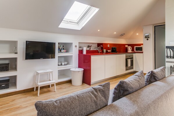 A modern kitchen with a red countertop, white cabinets, and a skylight.